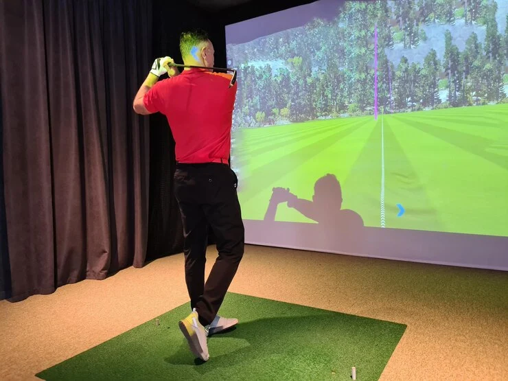 Man playing golf at indoor gold simulator